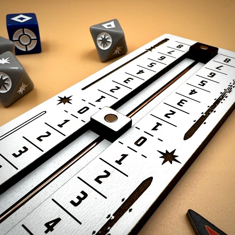 May include: A white game board with black numbers and a sliding metal bar. The numbers on the board range from 1 to 9. The board is used for a game of chance.