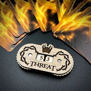 May include: A wooden counter with a crown design and the word "THREAT" printed on it. The counter has two dials that show the numbers 5 and 3.