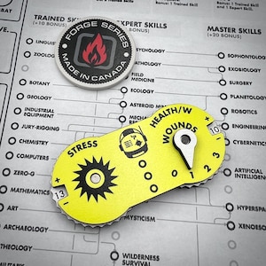 Puede incluir: Un contador de juego ovalado amarillo con un dial de estr&eacute;s negro en forma de engranaje que muestra 13, un dial de salud y heridas con un puntero met&aacute;lico en 1 y un icono de casco. Arriba hay una ficha redonda Forge Series Made in Canada.
