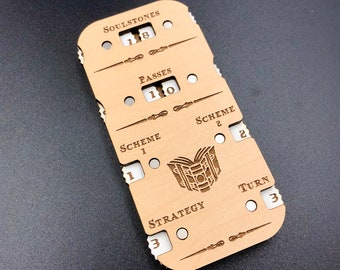 May include: A wooden game tracker with a brown background and white text. The tracker has sections for Soulstones, Passes, Scheme 1, Scheme 2, Strategy, and Turn. The tracker also features a stylized image of a book.