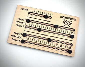 Könnte beinhalten: Ein Holzspielbrett mit einem Hobgoblin-Thema. Das Brett hat einen runden Zähler, zwei Siegzähler und zwei Quecksilberzähler. Das Brett ist mit den Worten "Round", "Victory" und "Mercury" beschriftet.