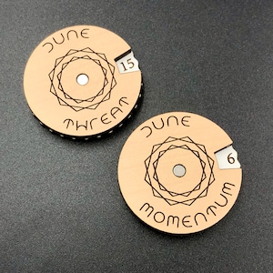 May include: Two wooden circular discs with a geometric design and the words "June Dream" and "June Momentum" on them. The discs have a number, 15 and 6, on them.