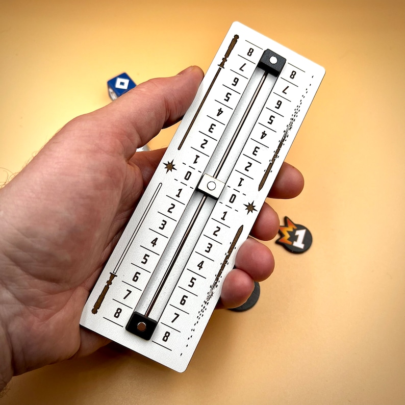 May include: A white wooden slider with black numbers 1 through 8 on each side. The slider is used to track points in a game.