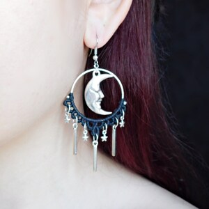 May include: Black and silver dangle earrings with a crescent moon charm and star accents.