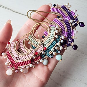 May include: A set of five colorful macrame earrings with gold hoops and various beads, including white pearls, red, purple, and green stones.