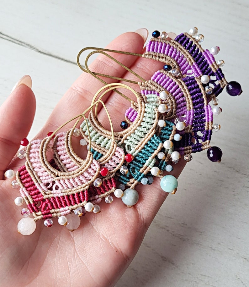 May include: A set of five colorful macrame earrings with gold hoops and various beads, including white pearls, red, purple, and green stones.