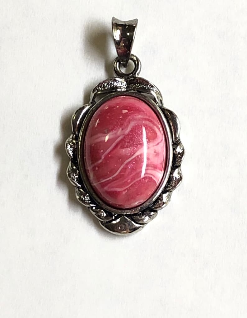 May include: A silver pendant with a pink and white oval stone set in a twisted rope design.