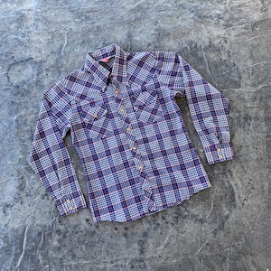 May include: A long-sleeved plaid shirt with a blue, white and red pattern. The shirt has a button-down collar and two chest pockets.