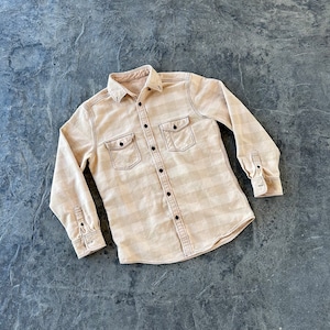 May include: A beige long-sleeved button-down shirt with a plaid pattern and black buttons. The shirt has two chest pockets with black stitching.