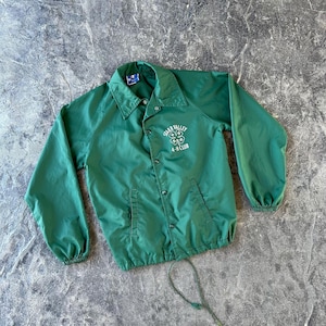 May include: A green vintage windbreaker jacket with a button-up front, collar, and long sleeves. The jacket features the text "Star Valley 4-H Club" in white on the left chest. The jacket has two front pockets and a drawstring at the bottom.