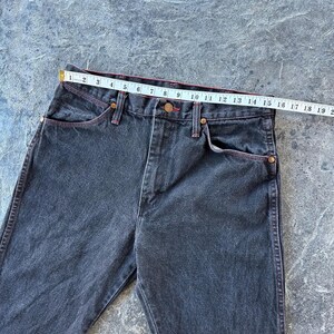May include: A pair of dark wash denim jeans with red stitching. The jeans have a straight leg and a classic five-pocket style.