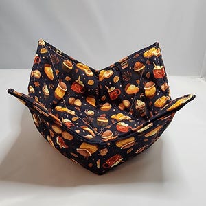 May include: A black fabric bowl with a fall-themed print of pastries, coffee cups, and cinnamon sticks. The bowl is folded and ready to use.