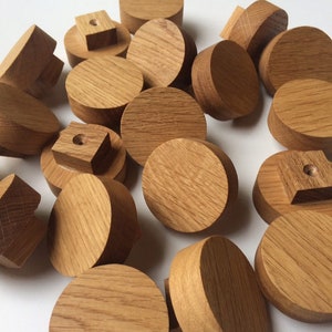 Puede incluir: Una colecci&oacute;n de pomos y tapones de madera sin terminar, de color marr&oacute;n claro. Las formas var&iacute;an, incluyendo formas redondas, cuadradas y cil&iacute;ndricas. La veta de la madera es visible. Estos componentes parecen ser para muebles o proyectos de artesan&iacute;a. Medidas en cent&iacute;metros.