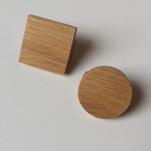 Può includere: Due pomelli per mobili in legno, uno quadrato e uno rotondo, entrambi con finitura a venatura naturale. Il pomello quadrato misura circa 4 cm di larghezza e quello rotondo ha un diametro di circa 4 cm. Questi pomelli sono ideali per mobili.