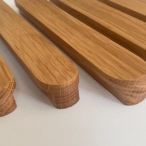 Könnte beinhalten: Nahaufnahme mehrerer rechteckiger Holzobjekte mit abgerundeten Kanten. Die Objekte sind hellbraun und scheinen aus Holz zu sein. Die Maserung des Holzes ist sichtbar. Die Objekte sind in einer Reihe angeordnet.