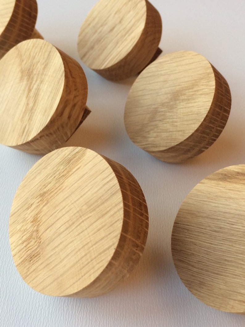 Puede incluir: Una colecci&oacute;n de pomos redondos de madera clara con un patr&oacute;n de vetas de madera natural. Los pomos son cil&iacute;ndricos con una parte superior e inferior planas y un borde ligeramente m&aacute;s oscuro. Probablemente son para muebles.