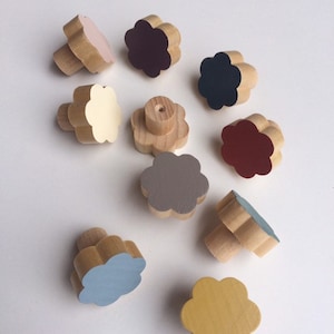 May include: A collection of wooden flower-shaped knobs in various colors, including pink, burgundy, navy, cream, gray, red, light blue, and yellow. The knobs are made of natural wood and are likely for furniture or decorative use.