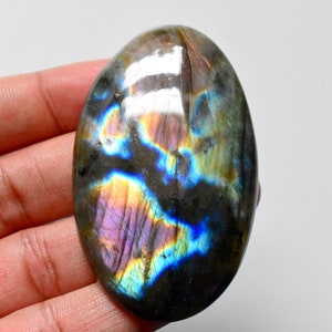 Può includere: Una grande pietra preziosa di labradorite di forma ovale con colori iridescenti blu, verdi e viola. La pietra è lucidata e ha una superficie liscia.