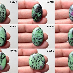 May include: Nine oval-shaped green gemstones with black and pink inclusions. The stones are labeled with the numbers B4947, B4948, B4949, B4950, B4951, B4952, B4953, B4954, and B4955.