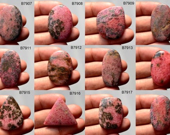 Puede incluir: Doce cabujones de rodocrosita rosa y negra de forma ovalada y triangular. Las piedras están dispuestas en cuatro filas de tres. Cada piedra está etiquetada con un número de identificación único.