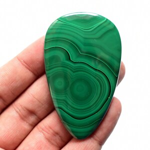 May include: A green malachite cabochon with a teardrop shape and swirling patterns.