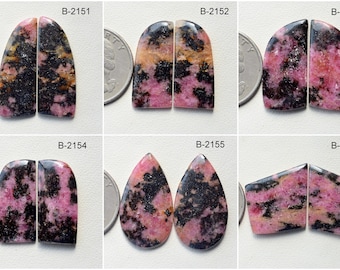 Puede incluir: Seis pares de piedras preciosas cabujón de color rosa y negro, cada par etiquetado con un código único, del B-2151 al B-2156. Las piedras preciosas se muestran sobre una superficie blanca junto a una moneda de veinticinco centavos de dólar estadounidense para la escala.