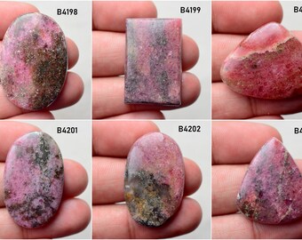 May include: Six cabochon cut pink rhodochrosite gemstones with varying patterns and shades of pink and gray. The stones are labeled with the codes B4198, B4199, B4200, B4201, B4202, and B4203.