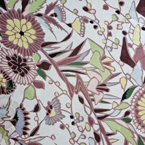 May include: A white fabric with a floral pattern. The flowers are pink, yellow, green, and blue. The fabric has a vintage look.