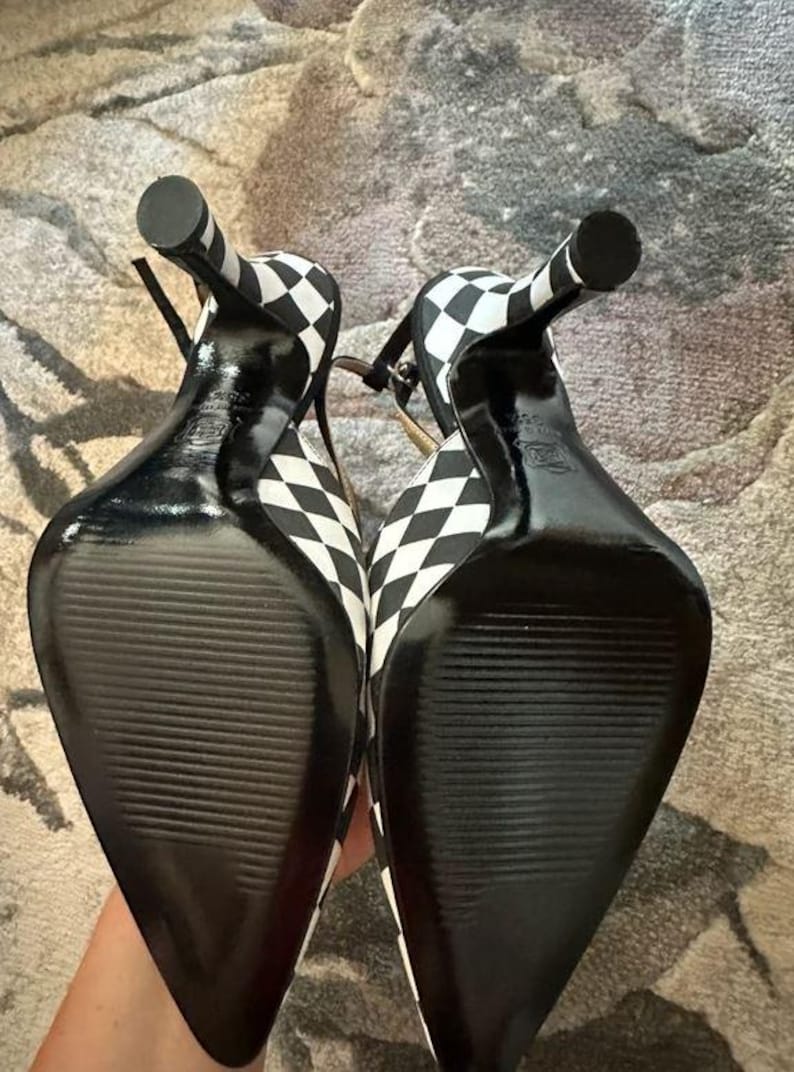 Puede incluir: Par de zapatos de tac&oacute;n alto con un estampado de cuadros blancos y negros. Los zapatos tienen punta afilada, finas correas en el tobillo y tac&oacute;n de aguja. Las suelas son negras con un dise&ntilde;o texturizado.