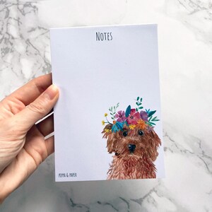 May include: A notepad featuring a brown dog wearing a colourful flower crown. The notepad says "NOTES" at the top and "PIPPA & PAPER" at the bottom.