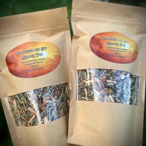 May include: Two brown paper bags filled with dried herbs and spices. The bags have labels that say "Happiness and Joy Simmer Pot" with a list of ingredients including "Peppermint, Lemongrass, Orange Peel, Basil".