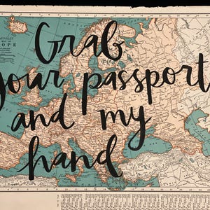 May include: A vintage map of Europe with teal and tan tones. The words "Grab your passport and my hand" are written in black cursive across the map. The map is from the Rand McNally World Atlas.