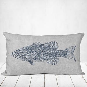 May include: A rectangular throw pillow featuring a textured light gray linen-like fabric. Centered on the front is a dark navy blue graphic illustration of a fish, rendered in a detailed, sketch-like style with visible scales and fins.