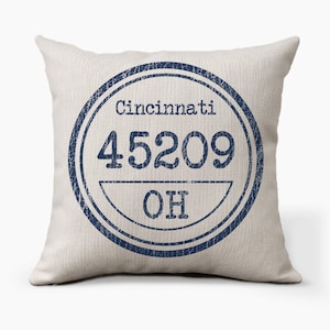 May include: A white throw pillow with a blue distressed circle design. The circle contains the text "Cincinnati 45209 OH".
