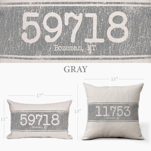 Op de afbeelding: Een rechthoekig kussen in grijs en wit met de tekst "59718 Bozeman, MT" erop gedrukt. Het kussen is 17 inch breed en 15 inch lang.