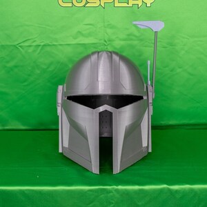 May include: A gray 3D printed helmet with a raised antenna and a visor. The helmet is on a green background with the text "PRINTING COSPLAY" in yellow.