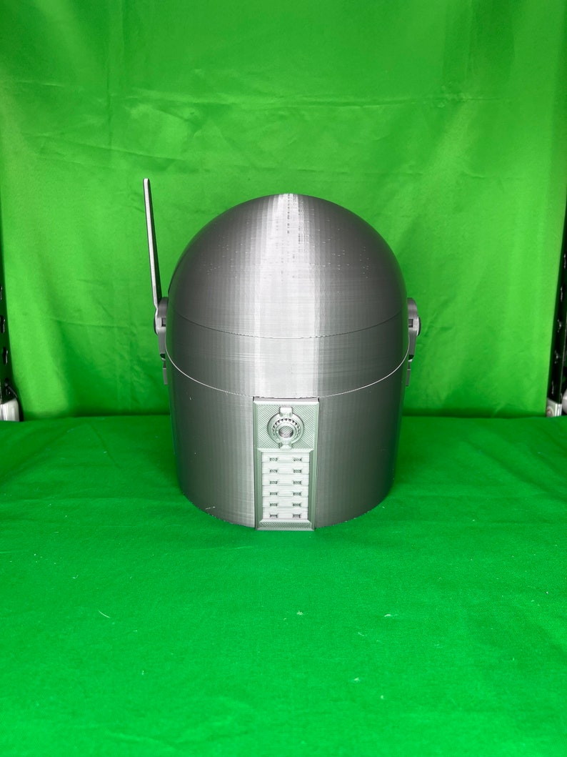 May include: A gray 3D printed helmet with a dome-shaped top and a panel of buttons on the front.