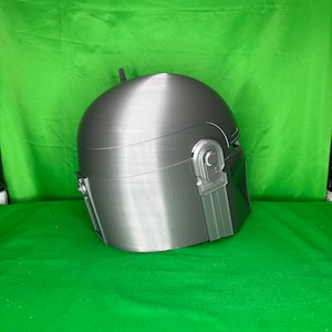 May include: A gray 3D printed helmet with a textured surface and a raised detail on the side.
