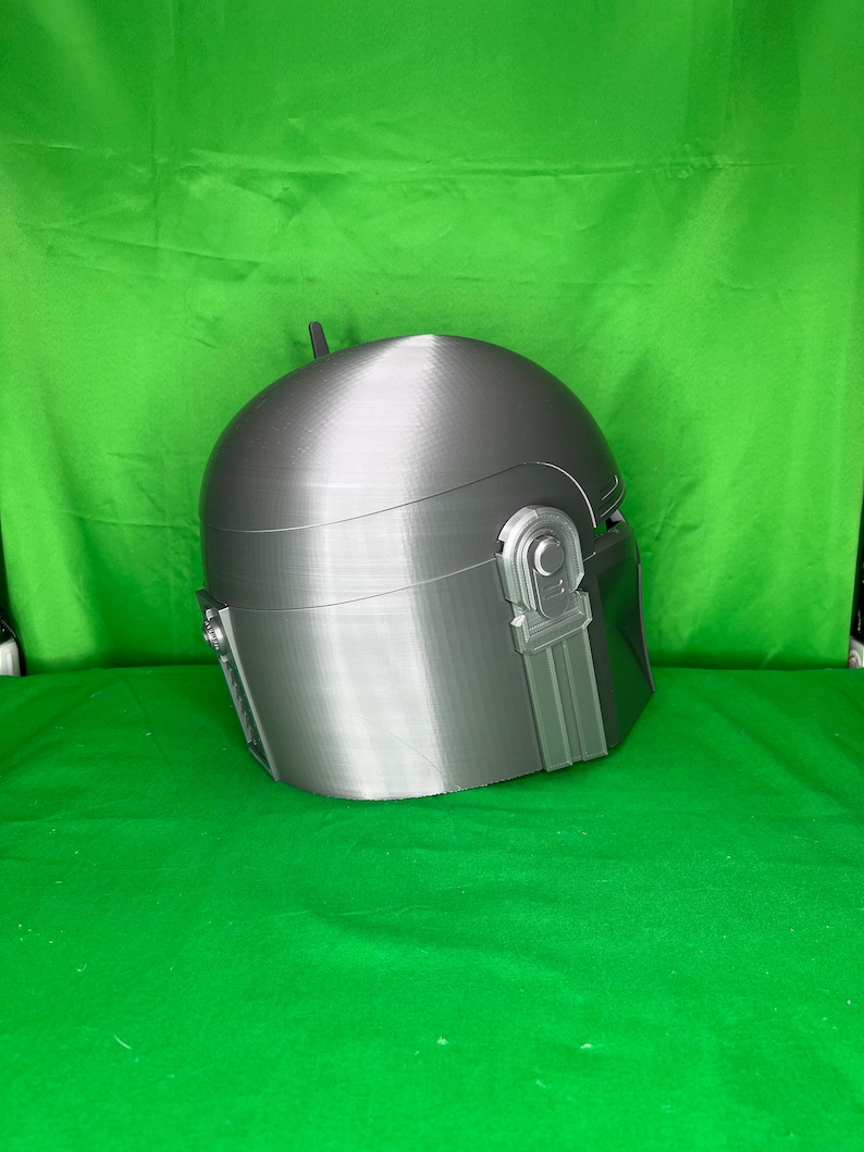 May include: A gray 3D printed helmet with a textured surface and a raised detail on the side.