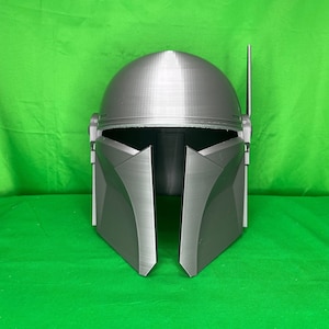 May include: A gray 3D printed helmet with a raised design. The helmet has a pointed top and a visor that is closed.