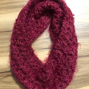 May include: A burgundy knitted infinity scarf with a fuzzy texture.