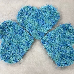 May include: Three blue and green heart-shaped crocheted trivets, arranged in a clover shape.