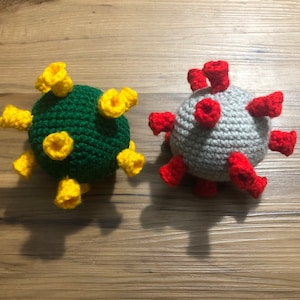May include: Two crocheted virus plush toys. One is green with yellow spikes and the other is gray with red spikes.