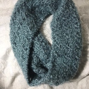 Może przedstawiać: Miękki, niebieski, puszysty szalik dziany. Szalik jest wykonany z grubego włóczki i ma luźny, otwarty splot.