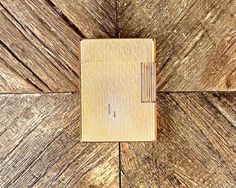 May include: A gold-coloured lighter with a textured surface and a red stripe on the side.