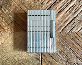 May include: A silver lighter with a grid pattern and the text "S.T. Dupont PARIS" on the side.