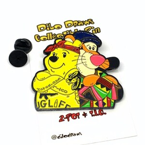 Pode incluir: Um broche de esmalte amarelo e laranja com o Winnie the Pooh e o Tigrão. O Pooh está usando uma bandana vermelha e tem uma tatuagem no braço que diz "Zorro-023N" e "IGLIFE". O Tigrão está usando um chapéu azul e uma camisa estampada colorida. O broche diz "2-POT + T.L.C." e "@dilodraws" na parte inferior.