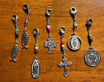 May include: Seven silver charm pendants with colourful beads. The charms include a fish, a cross, a Virgin Mary, and a Saint Francis of Assisi medal.