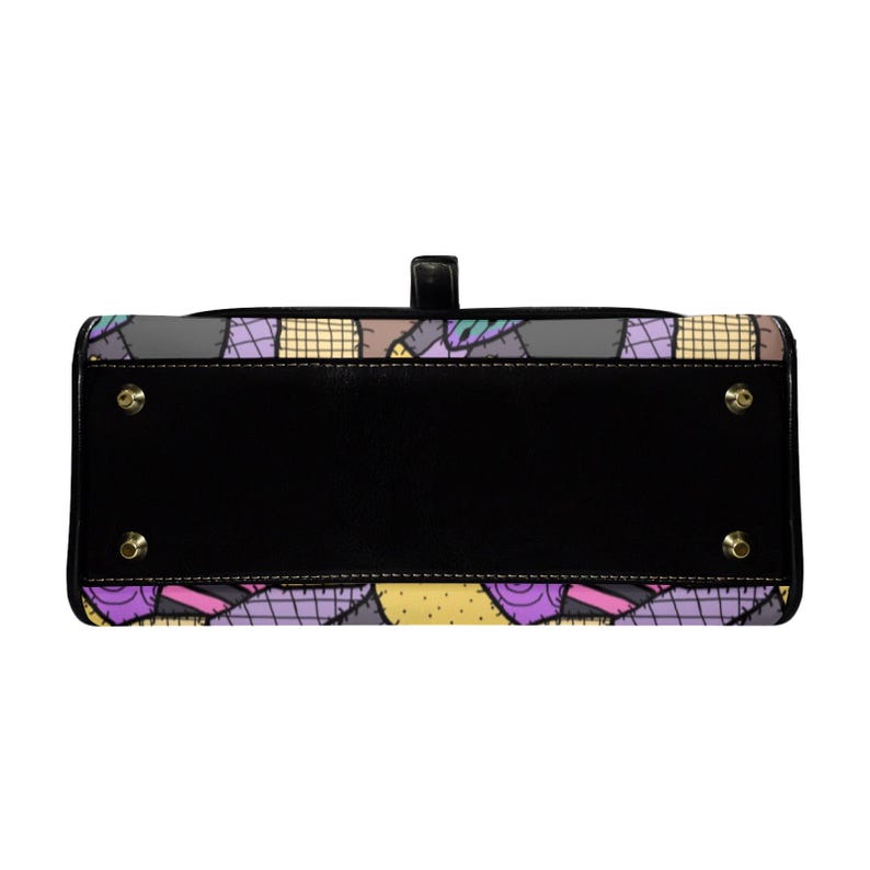 May include: Black handbag with a patchwork design featuring purple, yellow, and gray squares. The bag has a black base with gold-colored feet and a top handle. The patchwork pattern is reminiscent of a quilt.