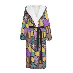 May include: A long-sleeved robe with a hood, featuring a patchwork design in shades of yellow, purple, and brown. The robe has a black tie belt and a white fleece lining.